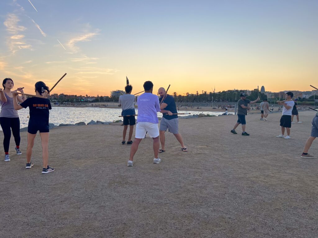Grupo de estudiantes en clase de artes marciales filipinas en la playa.